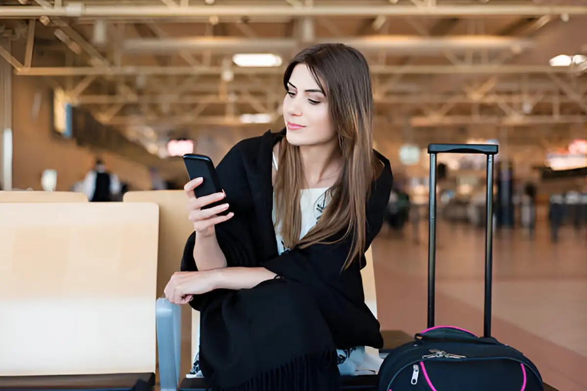 satisfied girl on the airport using mobile